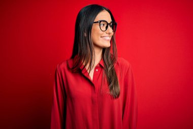 Genç, güzel, esmer bir kadın. Kırmızı arka planda gözlüklü, sıradan bir gömlek ve gözlük takıyor. Yüzünde gülümseme, doğal bir ifade var. Kendinden emin gülen.