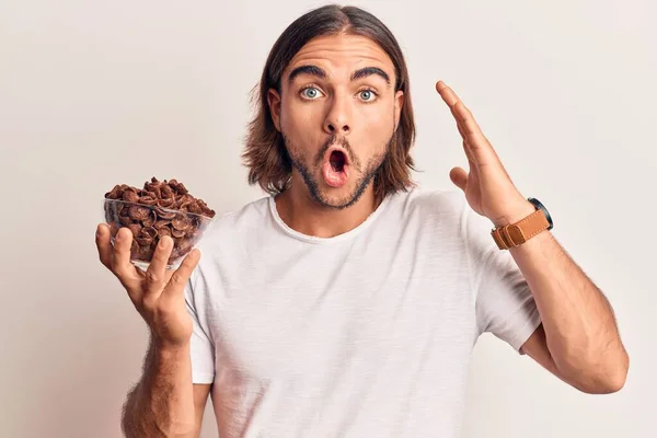 Νεαρός Όμορφος Άντρας Κρατώντας Δημητριακά Σοκολάτας Φοβισμένος Και Έκπληκτος Ανοιχτό — Φωτογραφία Αρχείου