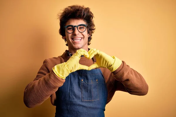 Młody Przystojniak Fartuchu Rękawiczkach Odizolowanym Żółtym Tle Uśmiechnięty Miłością Symbolami — Zdjęcie stockowe