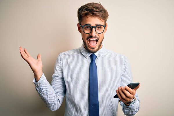 Young businessman having a conversation using smartphone over white background very happy and excited, winner expression celebrating victory screaming with big smile and raised hands