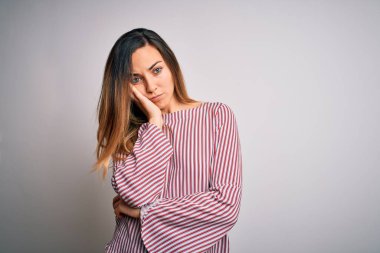 Genç, sarışın, mavi gözlü beyaz arka planda ince tişörtlü bir kadın. Kollarını kavuşturup depresyondan sıkılmış ve yorgun görünüyor..