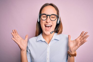 Genç, güzel çağrı merkezi ajanı, gözlük takan, kulaklık takan, başarıyı kutlayan, kollarını kaldırmış, gözlerini kapatmış, heyecanlı çığlıklar atan, çılgın kulaklık kullanan bir kadın. Kazanan konsept
