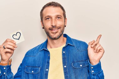 Yüreği tutan yakışıklı genç adam gülümseyen mutlu bir şekilde elini ve parmağını yana doğru uzat. 