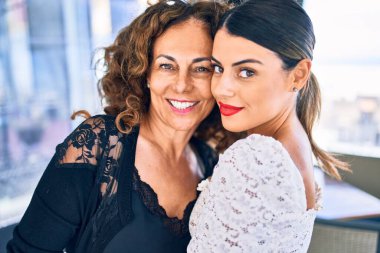 Güzel anne ve kız mutlu ve kendinden emin gülümsüyor. Gülümseyerek ayakta durup restoranda sarılıyorum.