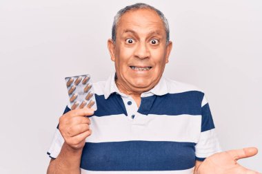 Son sınıf öğrencisi elinde haplarla başarıyı mutlu bir gülümsemeyle kutluyor ve kazanan el kaldırarak ifade ediyor. 