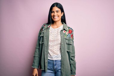 Genç, güzel İspanyol moda kadını pembe arka planda havalı bir ceket giyiyor ve yüzünde mutlu ve havalı bir gülümseme var. Şanslı kişi..