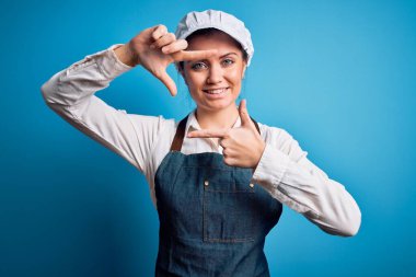 Mavi gözlü, mavi önlüklü, mavi arka planda şapkalı, gülümseyen, elleri ve parmakları mutlu yüzlü genç, güzel fırıncı kadın. Yaratıcılık ve fotoğrafçılık kavramı.