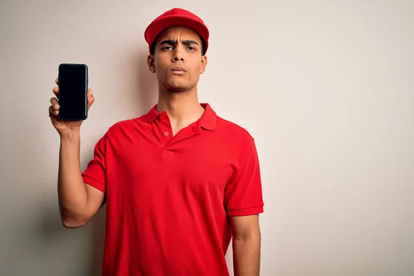 年轻英俊的非洲裔美国送货员 手持智能手机 带着自信的表情 带着严肃的表情 展示着屏幕应用程序 — 图库照片