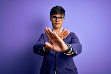 Ceket ve gözlük takan yakışıklı bir iş adamı. Mor arka planda. Reddedilmiş yüz ifadesi.