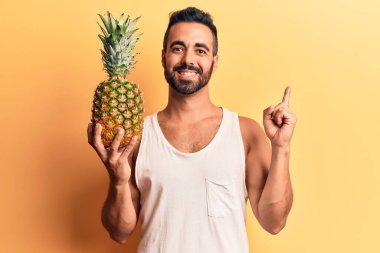 Ananas tutan genç İspanyol adam gülümsüyor mutlu bir şekilde elini ve parmağını yana uzatıyordu. 