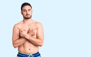 Mayo giyen genç ve yakışıklı bir adam her iki tarafı da parmaklarıyla işaret ediyor. Farklı yönlere bakıyor. 