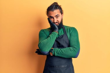 Berber önlük takan genç bir Arap, kollarını kavuşturarak depresyondan yorgun ve sıkılmış göründüğünü düşünüyor.. 