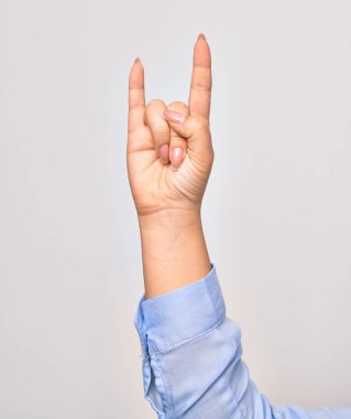 Beyaz arka planda boynuzları olan, kaya işareti yapan beyaz bir kadının eli.