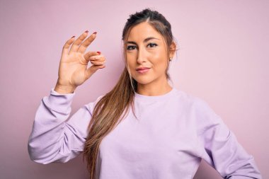 Genç ve güzel bir kadın pembe izole edilmiş arka planda Fransız pastası yiyor. Akıllı yüzünde kendine güvenen bir ifade var ve ciddi düşünüyor.