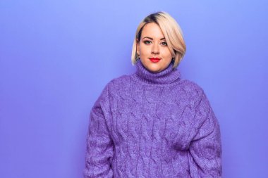 Güzel sarışın ve boyunda bir kadın mor arka planda balıkçı yaka kazak giyiyor. Uykulu ve yorgun görünüyor. Yorgun ve akşamdan kalma, tembel gözleri var..