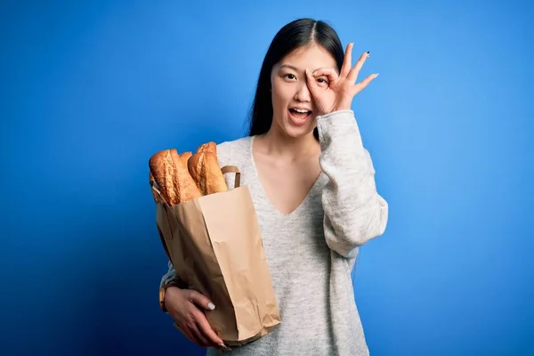 Jovem Asiático Mulher Segurando Pão Supermercado Papel Saco Sobre Azul — Fotografia de Stock