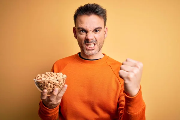 Jonge Knappe Man Met Een Schaal Vol Pinda Die Geïsoleerde — Stockfoto