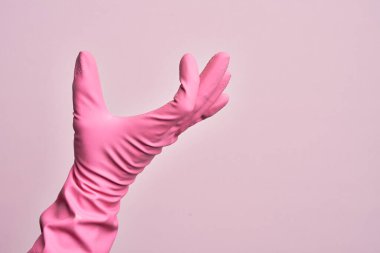 İzole edilmiş pembe arka plan üzerinde temizlik eldiveni olan beyaz bir adamın eli. Görünmez bir şeyi alıp, parmaklarında boşluk gösteren bir nesneyi tutuyor.