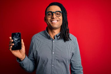 Genç Afro-Amerikan Afro-Amerikan adam elinde kırık bir akıllı telefon ile gülen bir yüzle ayakta duran ve gülümseyen dişlerini gösteren bir ekran gösteriyor.