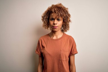 Güzel, kıvırcık saçlı, beyaz arka plan kuşkucu ve gergin beyaz tişörtlü Afro-Amerikalı kadın sorun yüzünden üzgün. Negatif kişi.