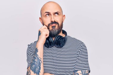 Müzik dinleyen genç yakışıklı adam kulaklıkla şüpheye odaklanmış, çenesinde parmak olan ve kafasını kaldırıp merak eden. 