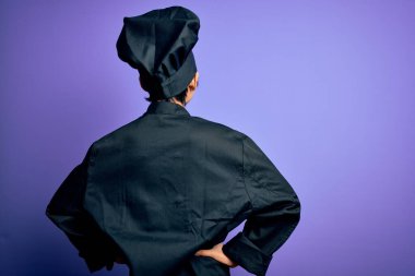 Genç, güzel Çinli aşçı kadın aşçı üniforması ve mor arka planda şapka takıyor geriye doğru bakıyor kolları vücudunda.