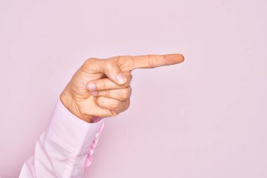 İzole edilmiş pembe arka plan üzerinde parmaklarını gösteren beyaz bir gencin eli işaret parmağıyla kenarı işaret ediyor ve bir seçim yapıyor.