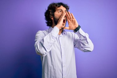 Mor arka planda duran sakallı yakışıklı iş adamı elleri ağzında sinirli bir şekilde bağırıyor.