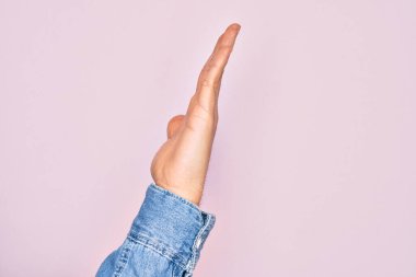 Kafkasyalı bir gencin elleri pembe arka planda parmaklarını gösteriyor. Uzanmış el hareketlerini gösteriyor, itiyor ve duruyor.