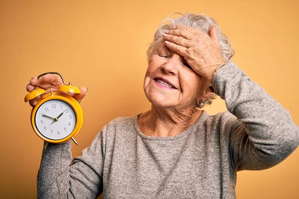 Sarı Arka Planda Çalar Saat Tutan Yaşlı Güzel Bir Kadın — Stok fotoğraf