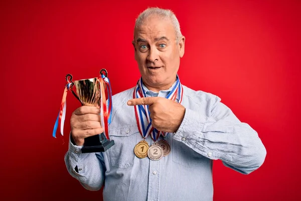 나이의 남자가 메달을걸 트로피를 손가락으로 행복하게 가리키고 있습니다 — 스톡 사진