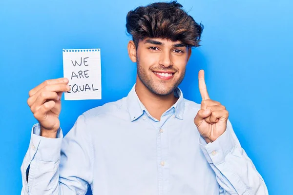 Jovem Hispânico Segurando Somos Papel Igual Sorrindo Com Uma Ideia — Fotografia de Stock