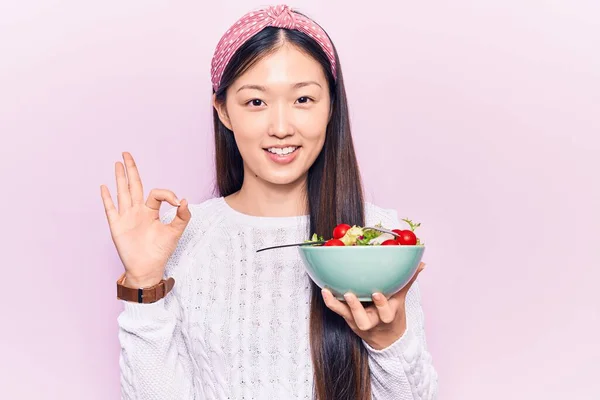 若い美しい中国の女性は指でOkサインを行うサラダとボウルを食べます 笑顔優しいジェスチャー優れたシンボル — ストック写真