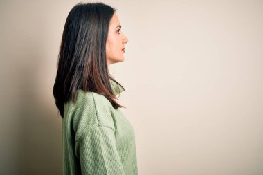 Mavi gözlü, beyaz arka planda balıkçı yaka kazak giyen genç, esmer bir kadın. Yan tarafa bakıyor, rahat bir poz veriyor, kendine güvenen bir gülümsemesi var..