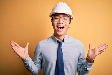 Güvenlik kaskı takan ve sarı arka planda kravat takan genç yakışıklı mimar başarıyı kutlarken kolları havada ve gözleri kapalı heyecanla bağırıyor. Kazanan konsept