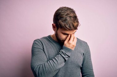 Sakallı, mavi gözlü, sıradan bir süveter giyen, burnu ve gözleri ovuşturan yorgun ve başı ağrıyan genç yakışıklı sarışın bir adam. Stres ve hüsran kavramı.