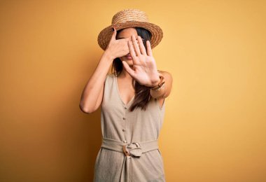 Genç ve güzel esmer kadın tatilde. Günlük elbiseler ve şapkalar takıyor. Gözlerini ellerle kapatıyor. Utanç verici ve olumsuz bir kavram..