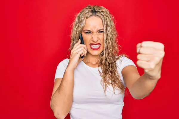 Vacker Blond Kvinna Som Pratar Smartphone Över Röd Bakgrund Irriterad — Stockfoto