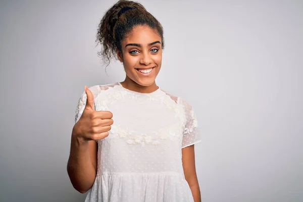 白い背景の上にカジュアルなTシャツを着た若い美しいアフリカ系アメリカ人の女の子が手で幸せな親指をジェスチャーをしています 成功を示すカメラを見て表現を承認する — ストック写真