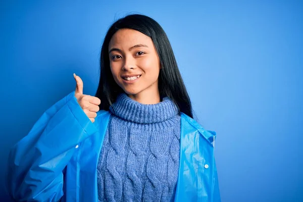 Fiatal Gyönyörű Kínai Visel Esőkabát Áll Elszigetelt Kék Háttér Csinál — Stock Fotó