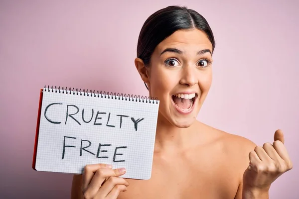 Young beautiful girl asking for cruelty free and vegan beauty cosmetics over pink background screaming proud and celebrating victory and success very excited, cheering emotion
