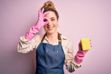 Güzel sarışın temizlikçi kadın ev işi yapıyor. Arpon ve eldiven takıyor. Gülümseyen kırbaç kullanıyor.