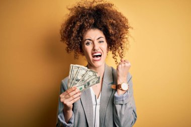 Kıvırcık saçlı ve elinde dolar tutan güzel bir kadın. Banknotlar. Sinirli ve sinirli bir şekilde bağırıyor.