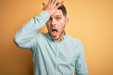 Sarı arka plan üzerinde zarif yeşil tişörtler giyen mavi gözlü genç bir iş adamı. Hatayla el ele tutuşurken şaşırdı. Hatayı hatırla. Unuttum, kötü hafıza konsepti.