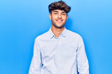 Yüzünde mutlu ve havalı bir gülümseme olan sıradan kıyafetler giyen genç İspanyol bir adam. şanslı kişi. 