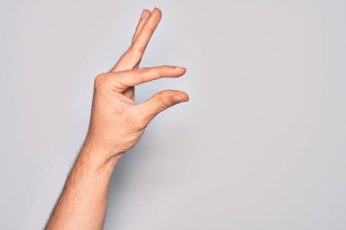 İzole edilmiş beyaz arka plan üzerinde parmaklarını gösteren beyaz bir adamın eli. Görünmez bir şeyi alıp, parmaklarıyla uzayı gösteren bir nesneyi tutuyor.