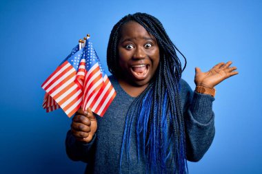Genç vatansever Afro-Amerikalı örgülü kadın. Birleşik Devletler bayrakları taşıyor. Çok mutlu ve heyecanlı.