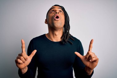 Siyah bir süveter giyen Afrikalı genç ve yakışıklı Amerikalı adam hayret ve şaşkınlık içinde yukarı baktı ve parmaklarıyla işaret etti ve kollarını kaldırdı..