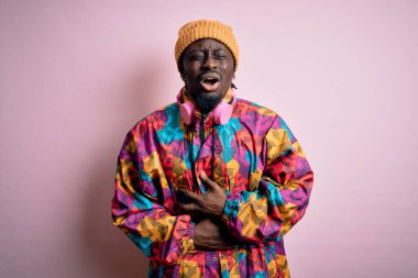 Mide bulantısı, acı verici bir hastalık yüzünden pembe arka planda pembe paltolu ve şapkalı genç, Afro-Amerikan adam. Ache kavramı.