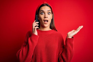 Genç, güzel esmer bir kadın akıllı telefonda konuşuyor. Çok mutlu ve heyecanlı. Kazanan ifade zaferi büyük bir gülümsemeyle kutluyor ve ellerini kaldırıyor.